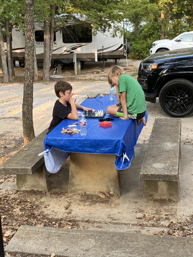 Boys camping and playing chess